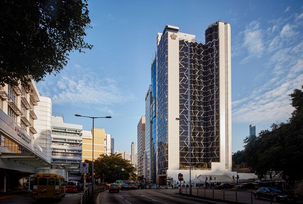A modern high-rise building with a distinctive geometric facade, surrounded by urban streets and other buildings. - The Emperor Hotel (Hong Kong)