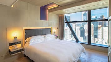 Een moderne hotelkamer met een groot bed, uitzicht over de stad en een uniek plafondontwerp.