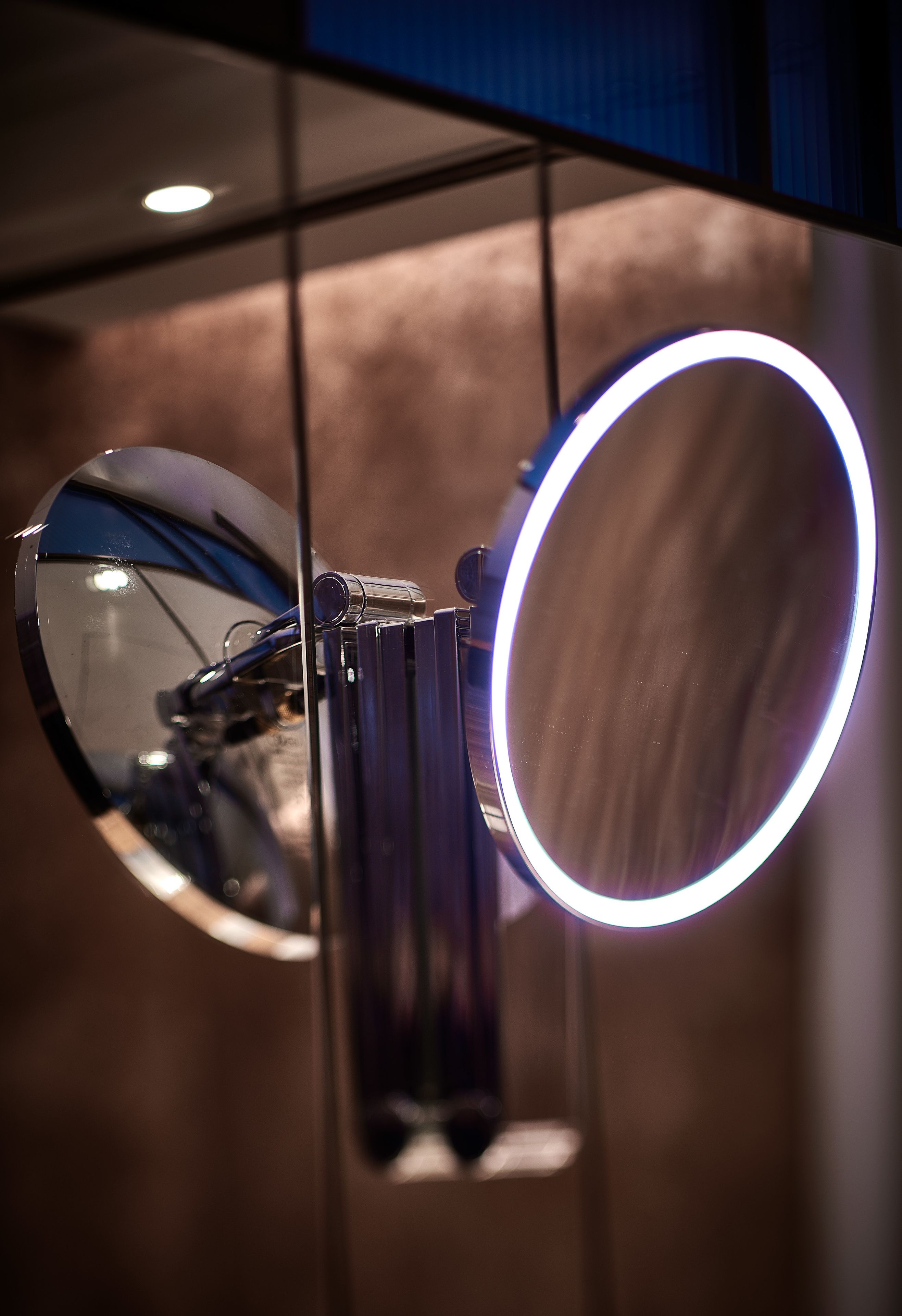A circular mirror with a light around its edge, mounted on a wall.