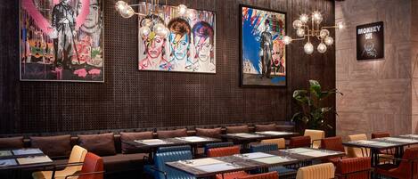 A restaurant with booths, tables, and colorful artwork on the walls.