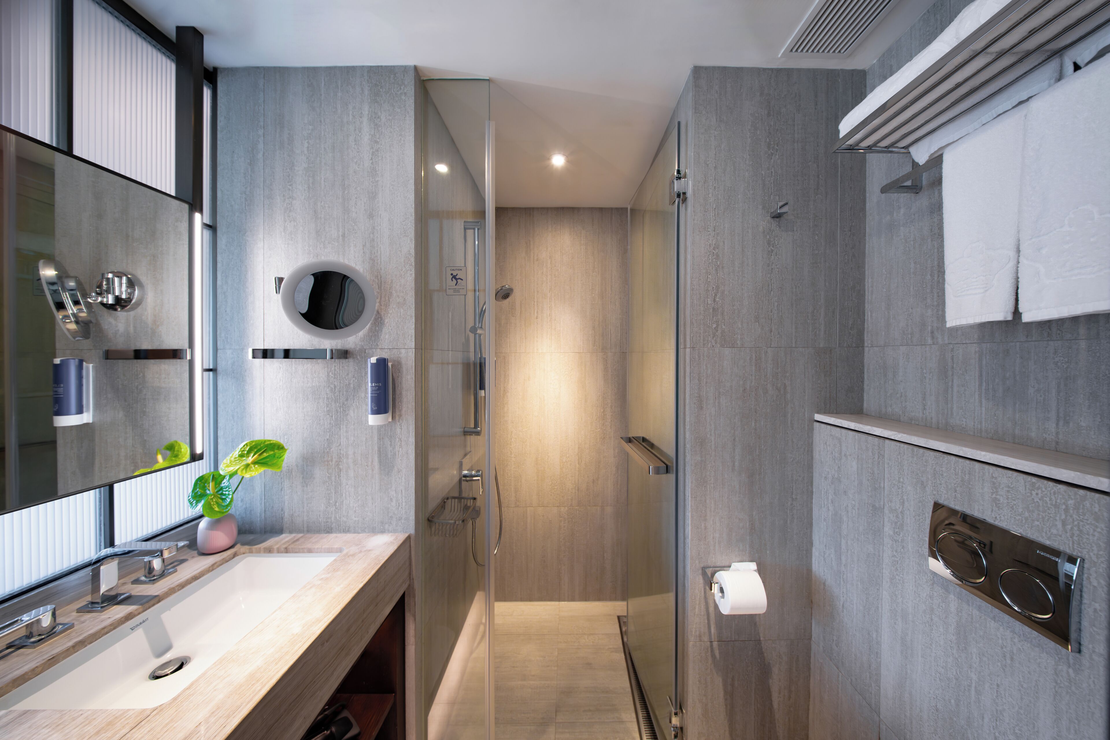 Une salle de bain moderne avec un grand miroir, un lavabo, une douche et un porte-serviettes.