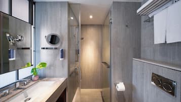 Une salle de bain moderne avec un grand miroir, un lavabo, une douche et un porte-serviettes.