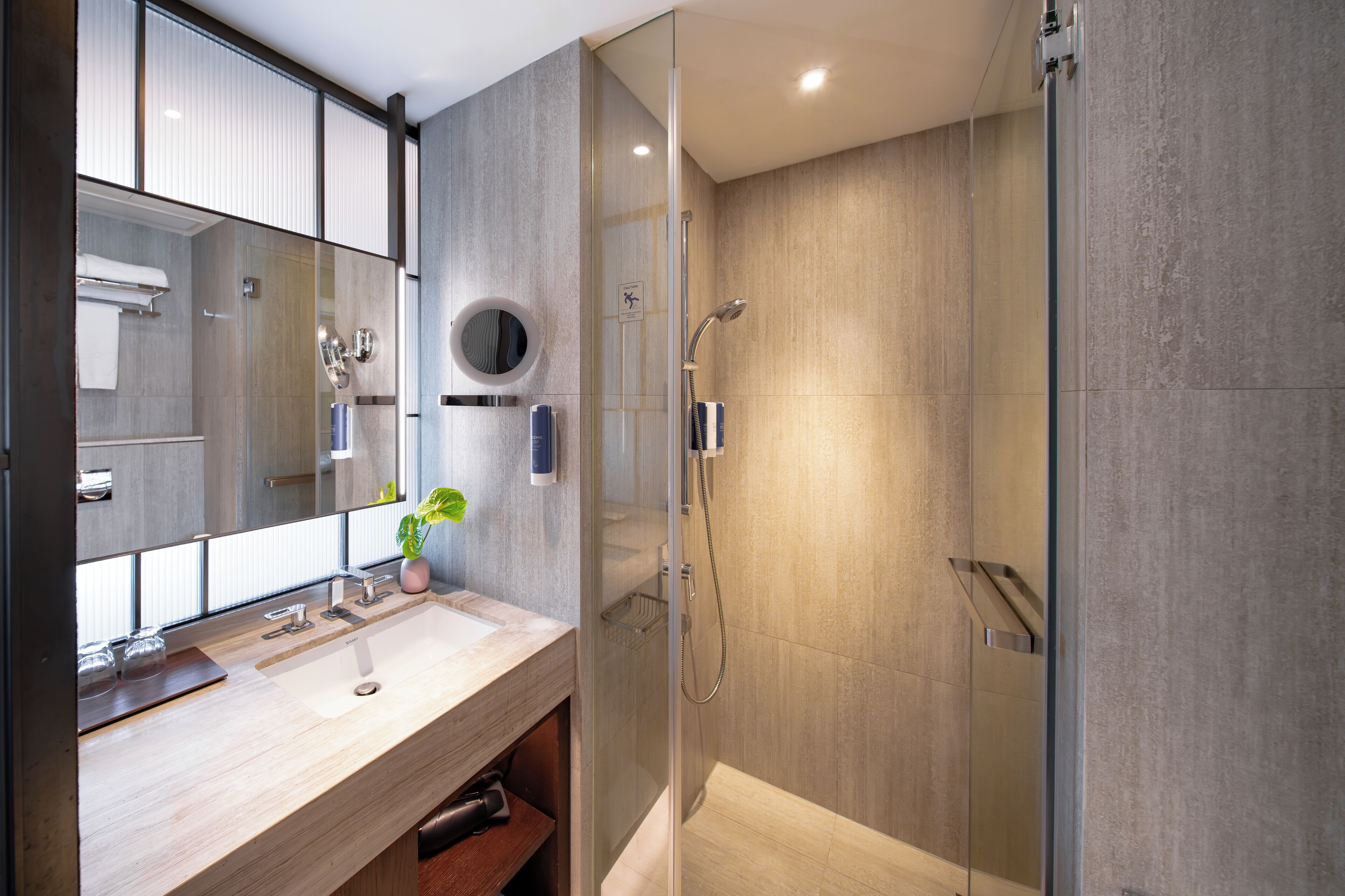 Un baño moderno con cabina de ducha acristalada, un espejo grande y un mueble de tocador de madera.