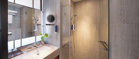 Un baño moderno con cabina de ducha acristalada, un espejo grande y un mueble de tocador de madera.