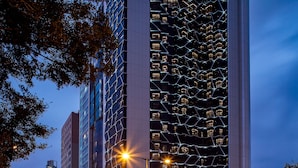 A modern high-rise building with a distinctive geometric facade and illuminated windows.