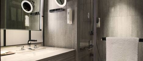 A modern bathroom with a glass-enclosed shower, a large mirror, and a wooden vanity.