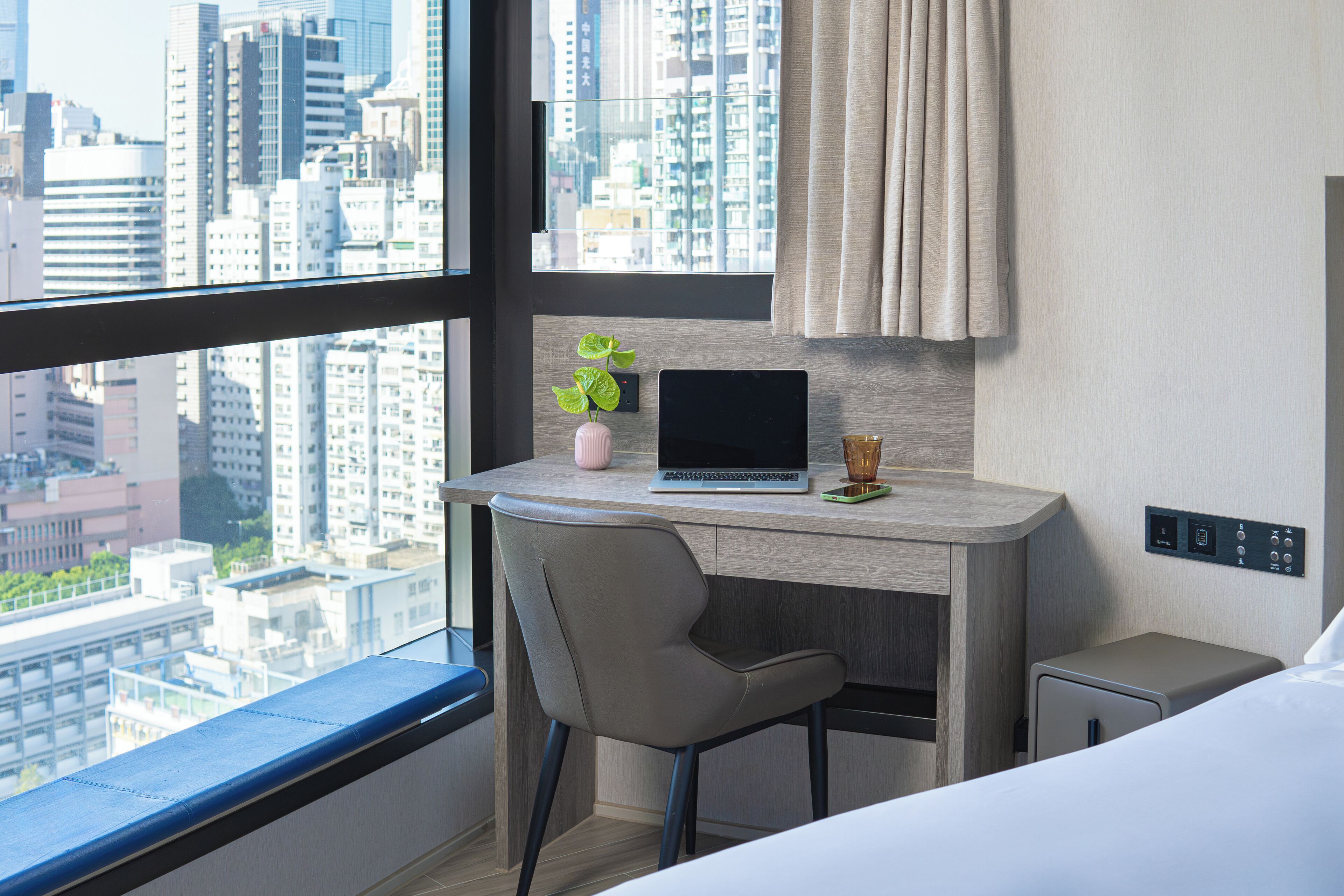 Una habitación de hotel moderna con un escritorio, una computadora portátil y vistas a la ciudad.