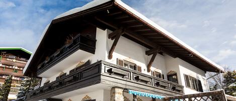Un chalet traditionnel doté d’un balcon, de piliers en pierre et d’un toit en bois.