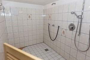 Un pequeño box de ducha con azulejos, con ducha de mano y manguera.