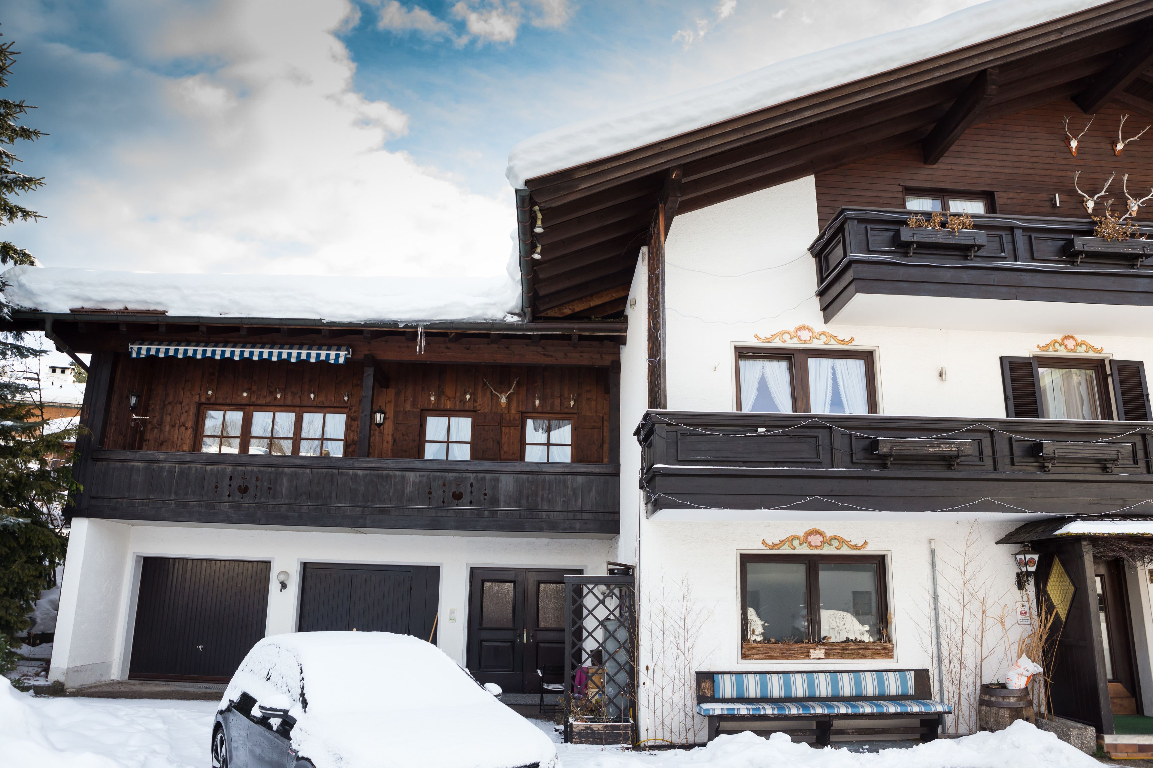A two-story building with a wooden facade, a balcony, and a bench outside.