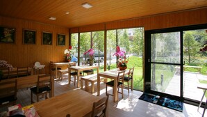 A modern interior with wooden walls and large windows. There are several wooden tables and chairs arranged for dining. - Xianel Vacation Chateau (Dahu)