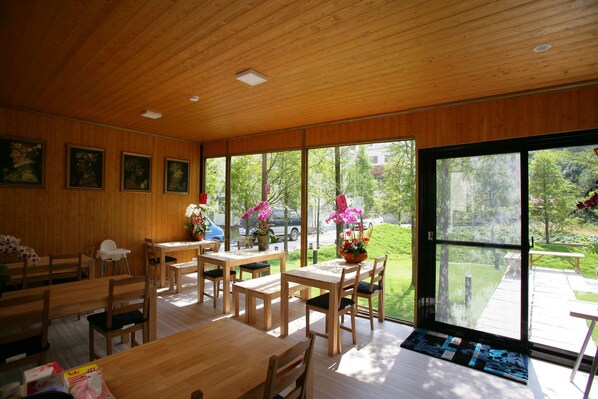 A modern interior with wooden walls and large windows. There are several wooden tables and chairs arranged for dining. - Xianel Vacation Chateau (Dahu)