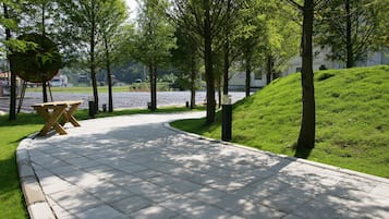 A paved pathway with a wooden bench and trees.