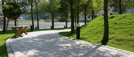 A paved pathway with a wooden bench and trees.