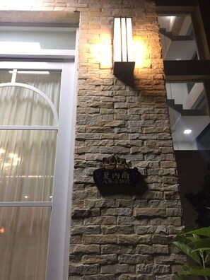 A stone wall with a sign and two wall-mounted lights. - Xianel Vacation Chateau (Dahu)