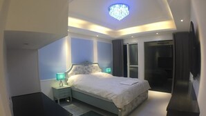 A modern bedroom with a bed, bedside tables, a chandelier, and a TV mounted on the wall. - Xianel Vacation Chateau (Dahu)