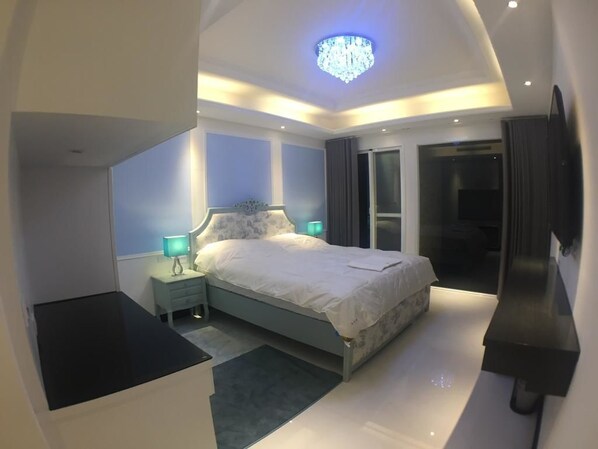 A modern bedroom with a bed, bedside tables, a chandelier, and a TV mounted on the wall. - Xianel Vacation Chateau (Dahu)
