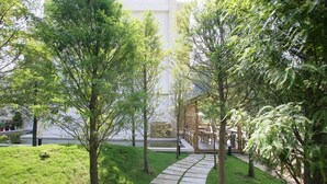 A pathway through a landscaped area with trees and a wooden deck. - Xianel Vacation Chateau (Dahu)