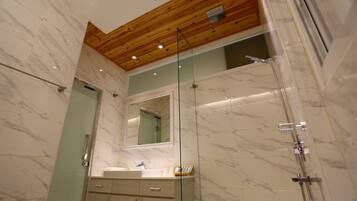 Une salle de bain moderne avec un plafond en bois, des murs en marbre, une douche en verre et un meuble-lavabo avec un miroir.