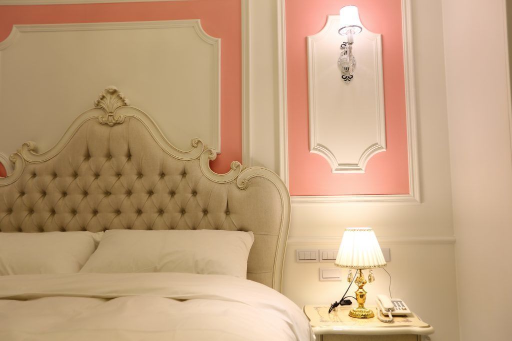 Ein Bett mit gebuschter Kopfteil, ein Nachttisch mit Lampe und eine Wandleuchte.
