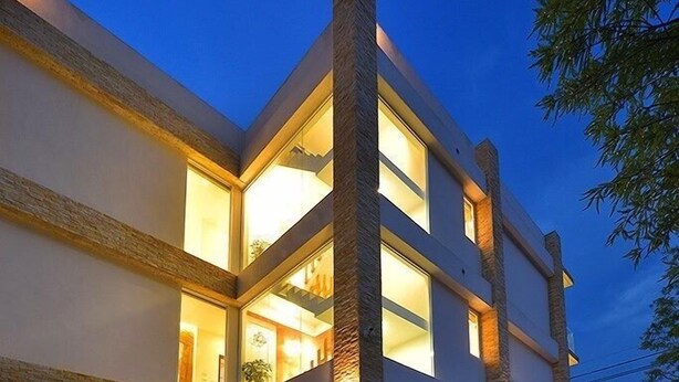 A modern multi-story building with large windows and a swimming pool area with water features. - Xianel Vacation Chateau (Dahu)