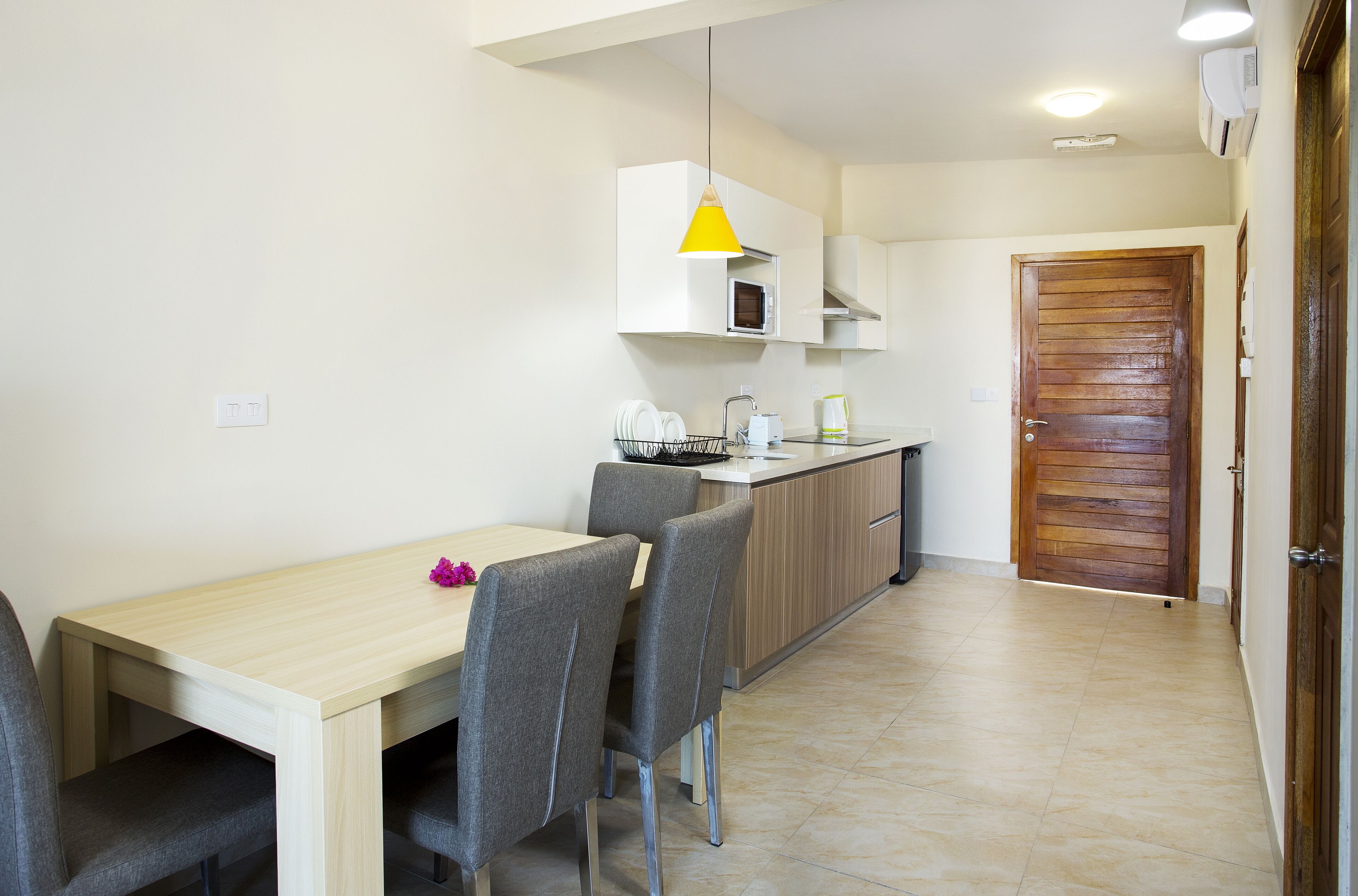 A compact kitchen with a dining area, a microwave, and a wooden door.