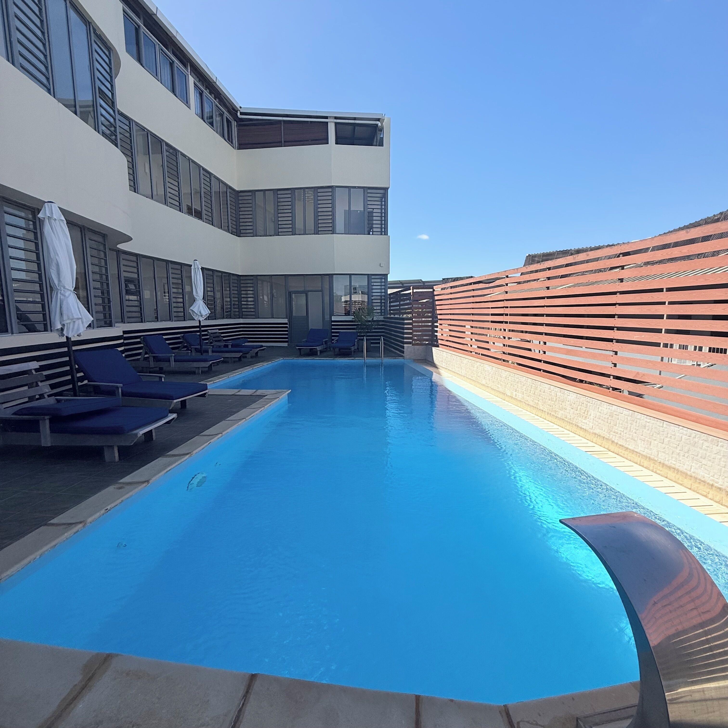 A pool area with lounge chairs and a building with large windows.