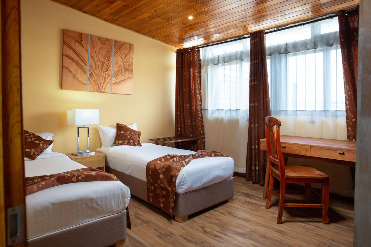 Une chambre d’hôtel avec deux lits, un bureau et une chaise.