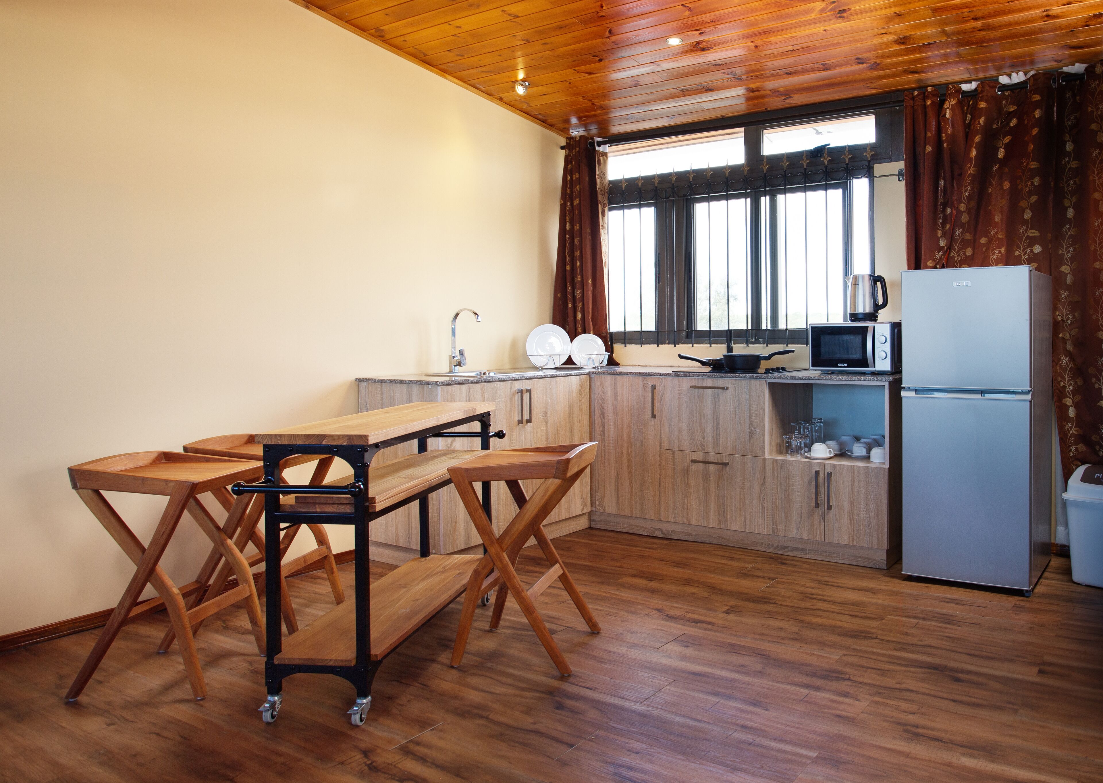 A compact kitchen with wooden cabinets, a sink, a microwave, and a refrigerator.