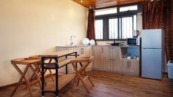 A compact kitchen with wooden cabinets, a sink, a microwave, and a refrigerator.
