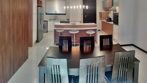 A modern kitchen with a central island, bar stools, and a dining area with chairs.