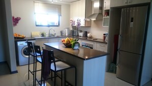 A modern kitchen with a central island, stainless steel appliances, and a window providing natural light.