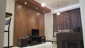 A modern living room with a wooden accent wall, a flat-screen TV, a sofa, and a coffee table.