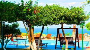 Zona de piscina con sillas de descanso, una hamaca y vista al mar.