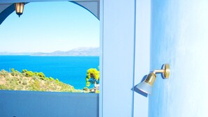 Una habitación con vistas al mar, una mesa, dos sillas y una lámpara de pared.