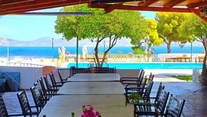 Un área de comedor al aire libre con vista al mar y a las montañas.