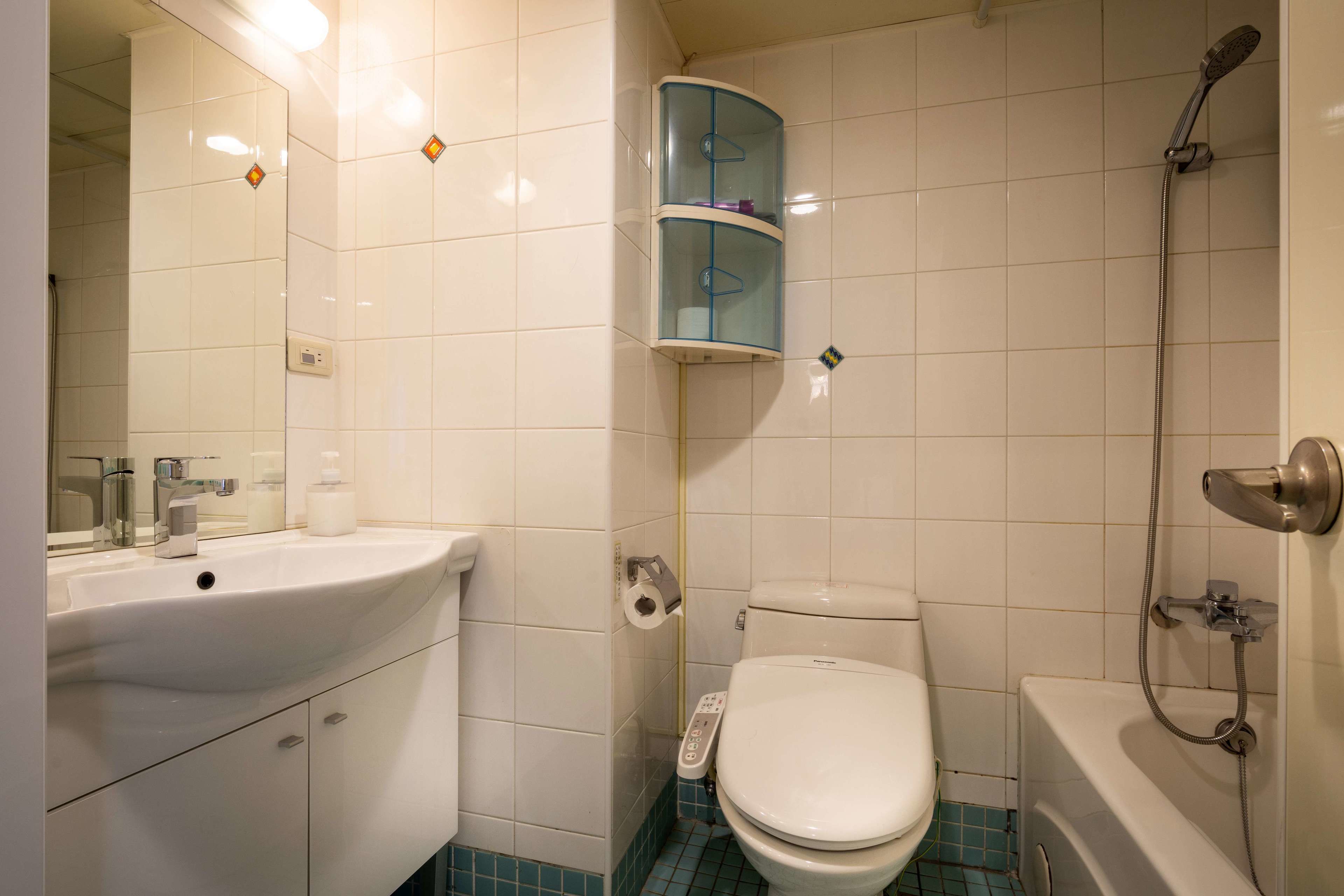 Une salle de bain avec un lavabo, des toilettes et une baignoire, tous de couleur blanche. On y trouve également une douche en verre et un miroir au-dessus du lavabo.