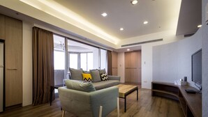 A modern living room with a sofa, a coffee table, and a TV stand. - Sky19 Hotel (Taipei)