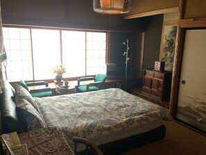Quarto com uma cama grande, uma escrivaninha, uma cadeira, um guarda-roupa e uma janela com vista.