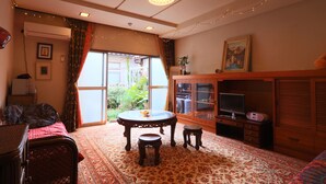 A room with a round table, two stools, a cabinet, and a television.