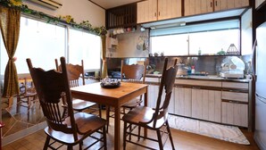 A dining area with wooden chairs and a table, a kitchen with wooden cabinets, and a window with a view.
