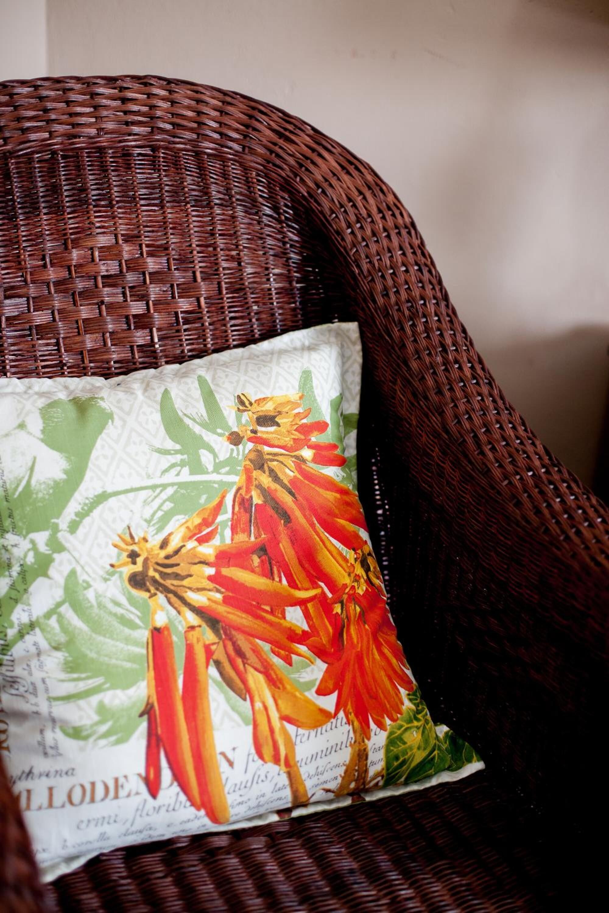 A wicker chair with a pillow featuring a floral design.