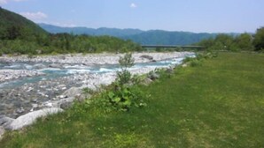 Un río de lecho rocoso, una zona cubierta de hierba a su lado y un puente a lo lejos.