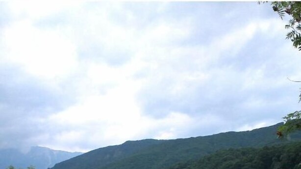 A grassy field with a rocky area and a mountain in the background. - Pension Hakuba OZ (Hakuba)