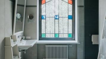 Un baño con ventana, lavamanos, espejo y baldosas de suelo estampadas.
