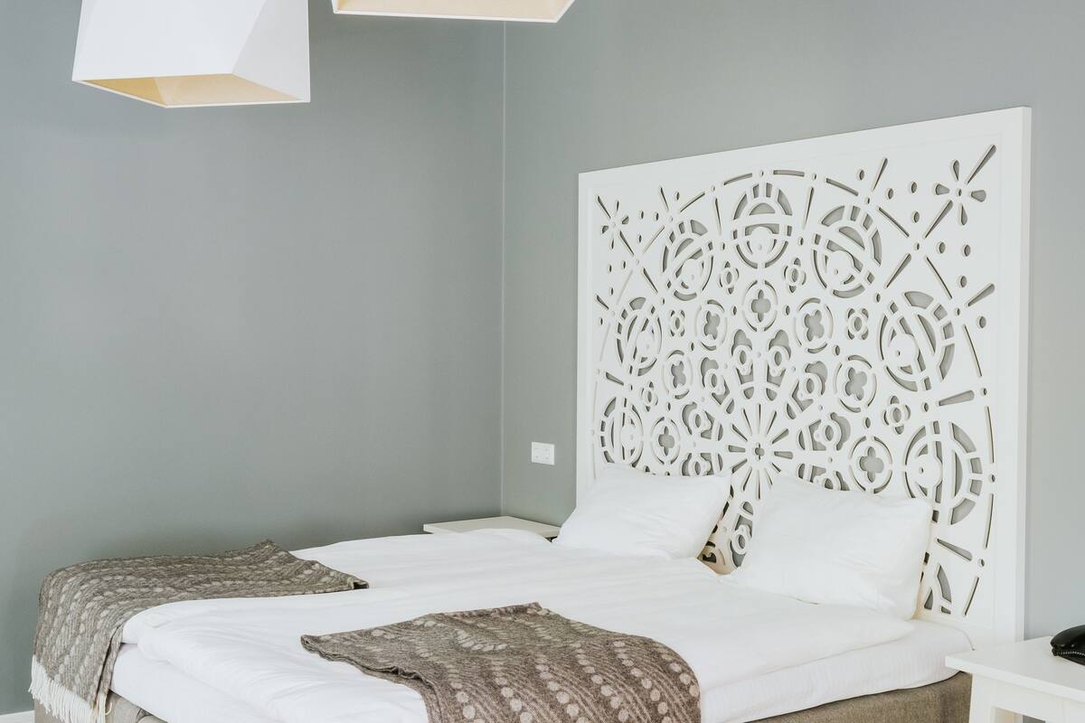 Un dormitorio moderno con una cama grande, un cabecero decorativo e iluminación colgante.
