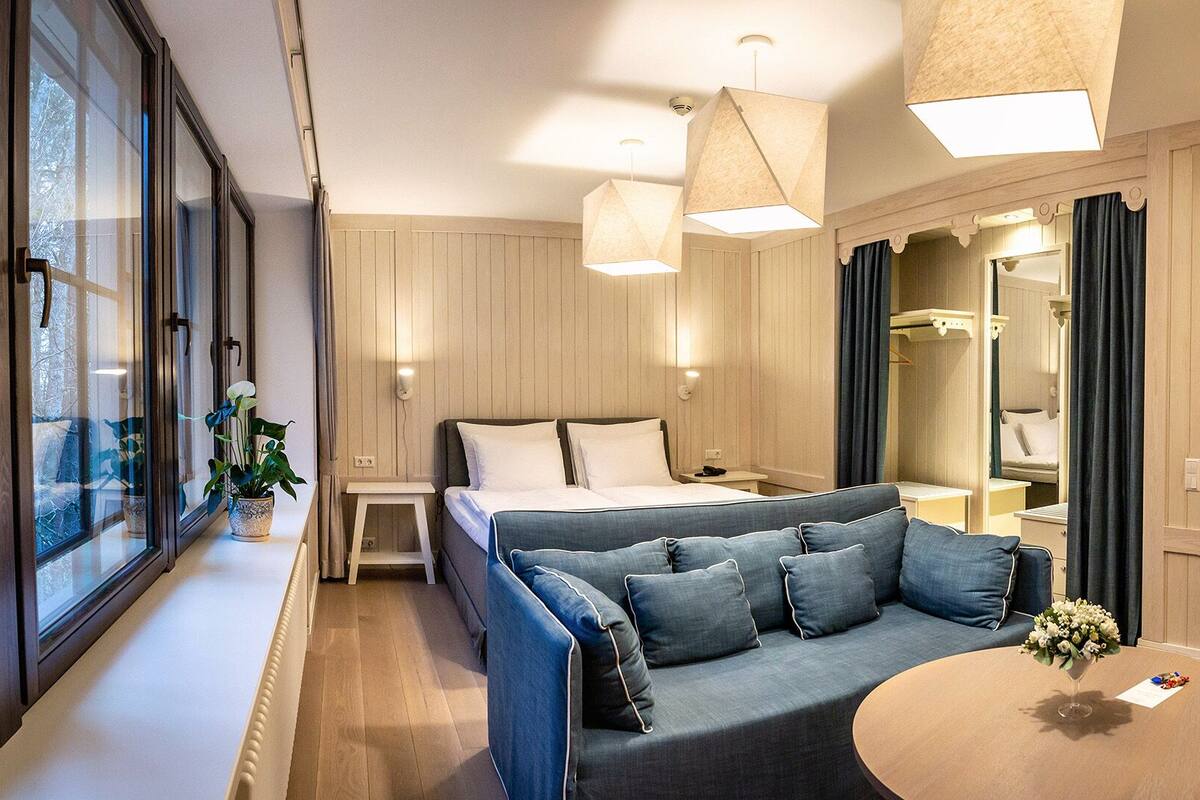 Una habitación de hotel moderna con una cama grande, un sofá, una mesita y un televisor.