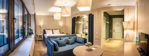 Ett modernt hotellrum med en stor säng, en soffa, ett litet bord och en TV.