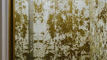 An elevator with a worn, peeling wall and a reflective floor.