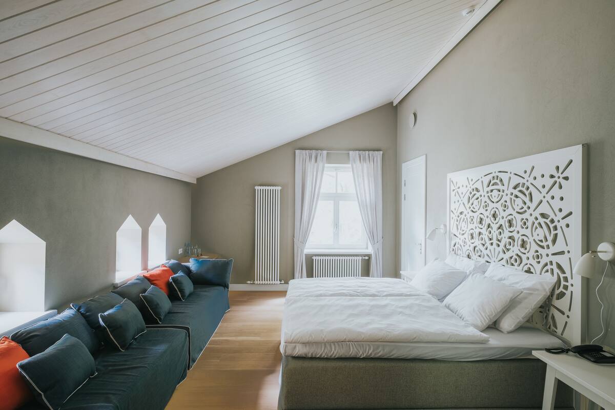 Un dormitorio moderno con una cama grande, un sofá y un radiador.